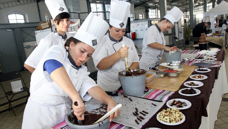 Élèves en toque blanche travaillant le chocolat fondu sur un stand de la Halle Marcadieu