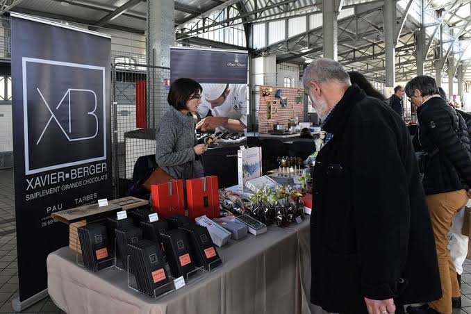 Visiteurs découvrant les coffrets du chocolatier Xavier Berger sous la halle
